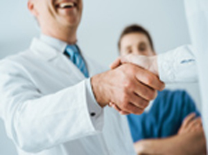 Smiling Male Physician shaking another males hand.